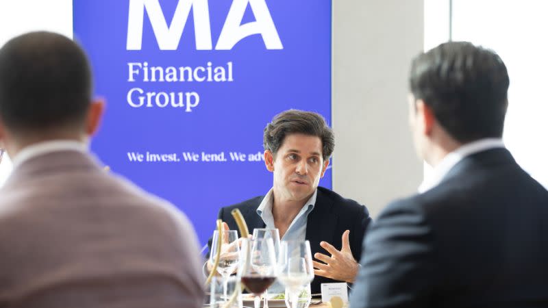 Three men sitting in front of a MA Financial Group banner