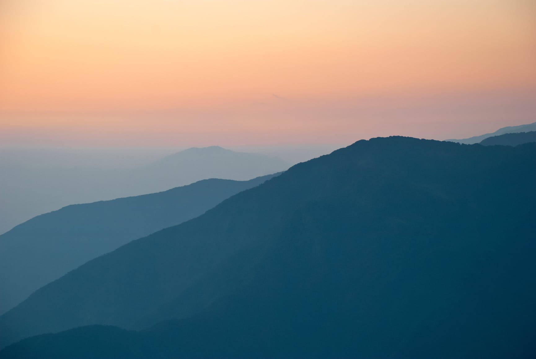 High angle image of the sun setting behind mountains.