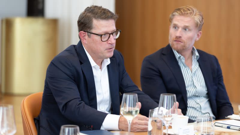 Two men in business suits sitting at a table with wine glasses