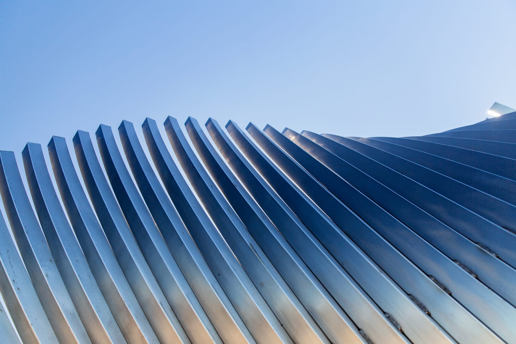 Architectural detail of a stainless steel building with an accordion pattern.