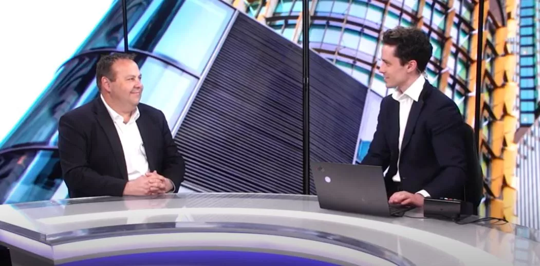 Two men in discussion at rounded table against the plasma backdrop of a building