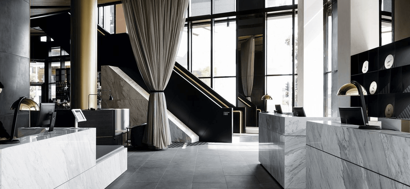 Reception of a hotel with marble reception desk and thick curtain.