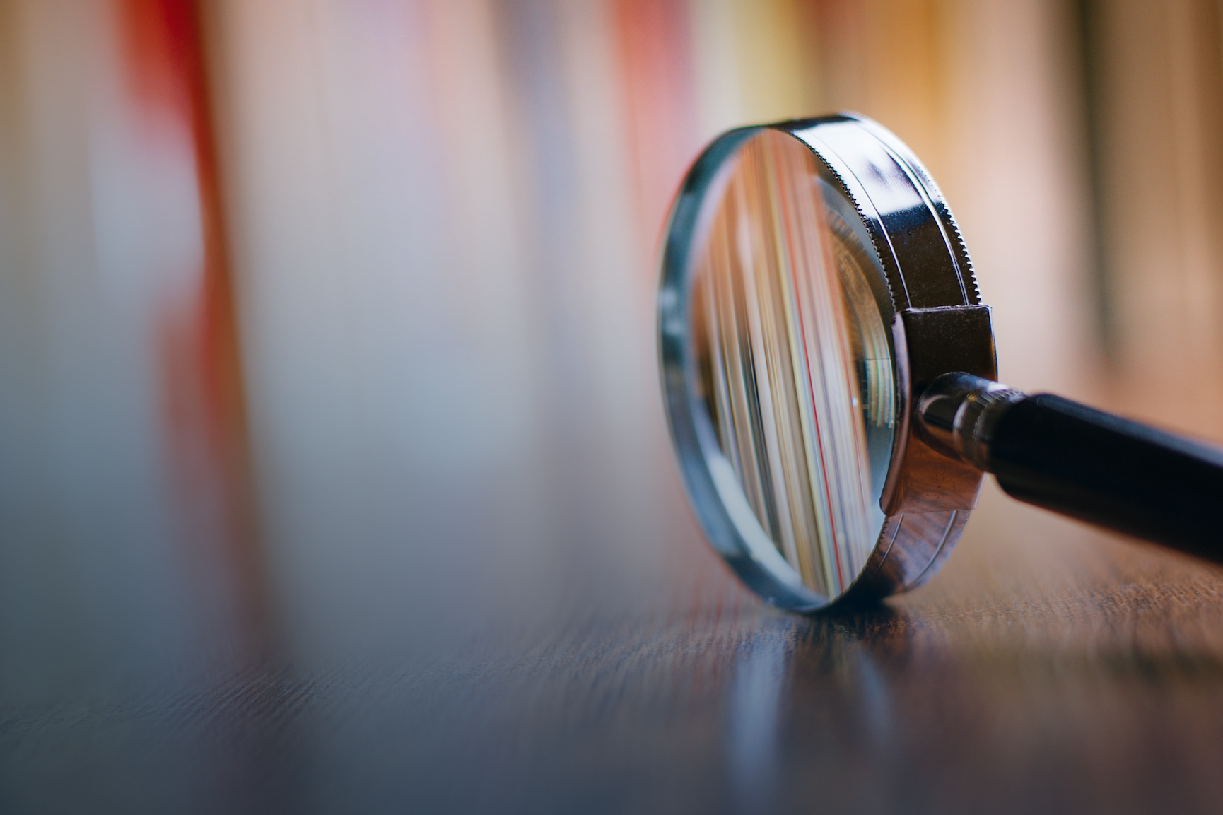 Magnifying glass on wooden table with blurry background
