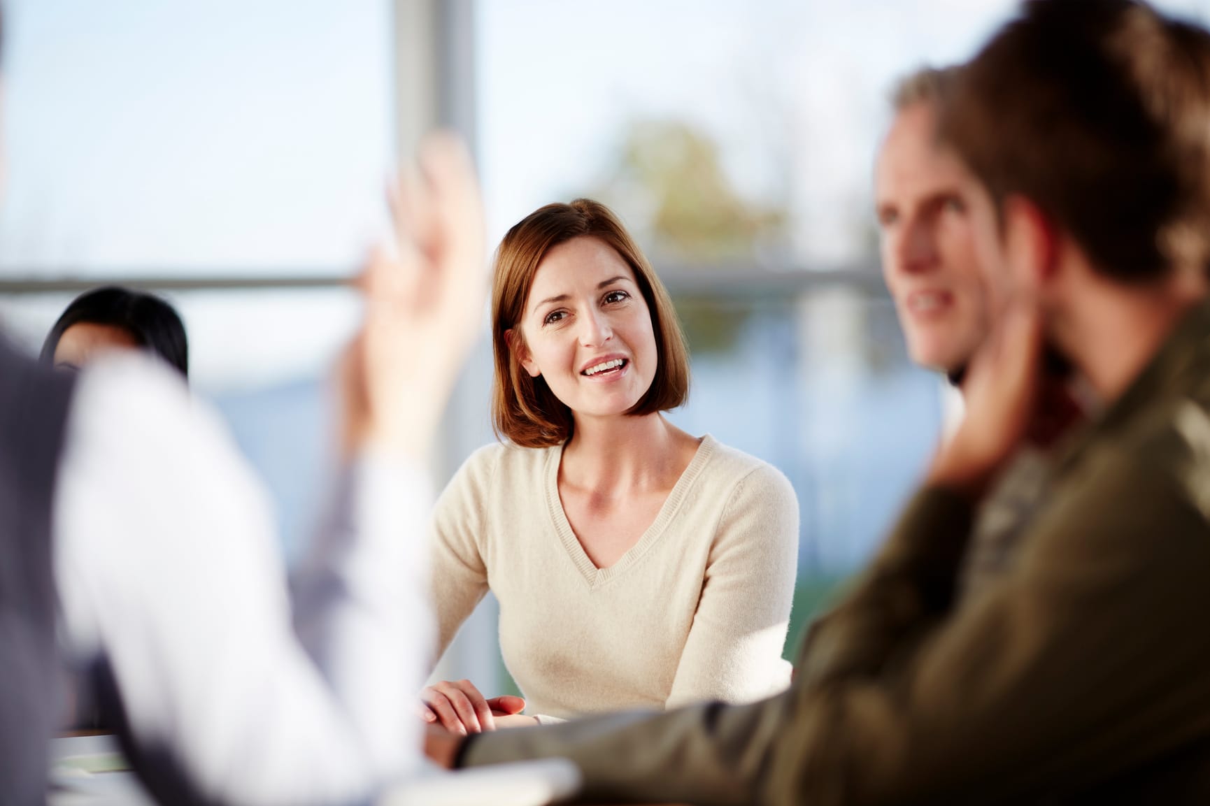 Woman with short brown hair in a meeting opening her mouth about to speak