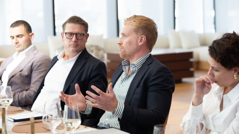 Four people sitting in a boardroom talking